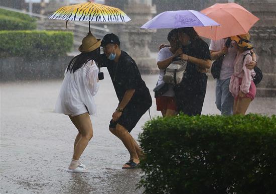 9月17日，三亚一景区内，游客们俩俩挤在伞下躲雨。当日，受今年第11号台风“红霞”影响和弱冷空气共同影响，海南陆地迎来明显降雨。人民视觉 图